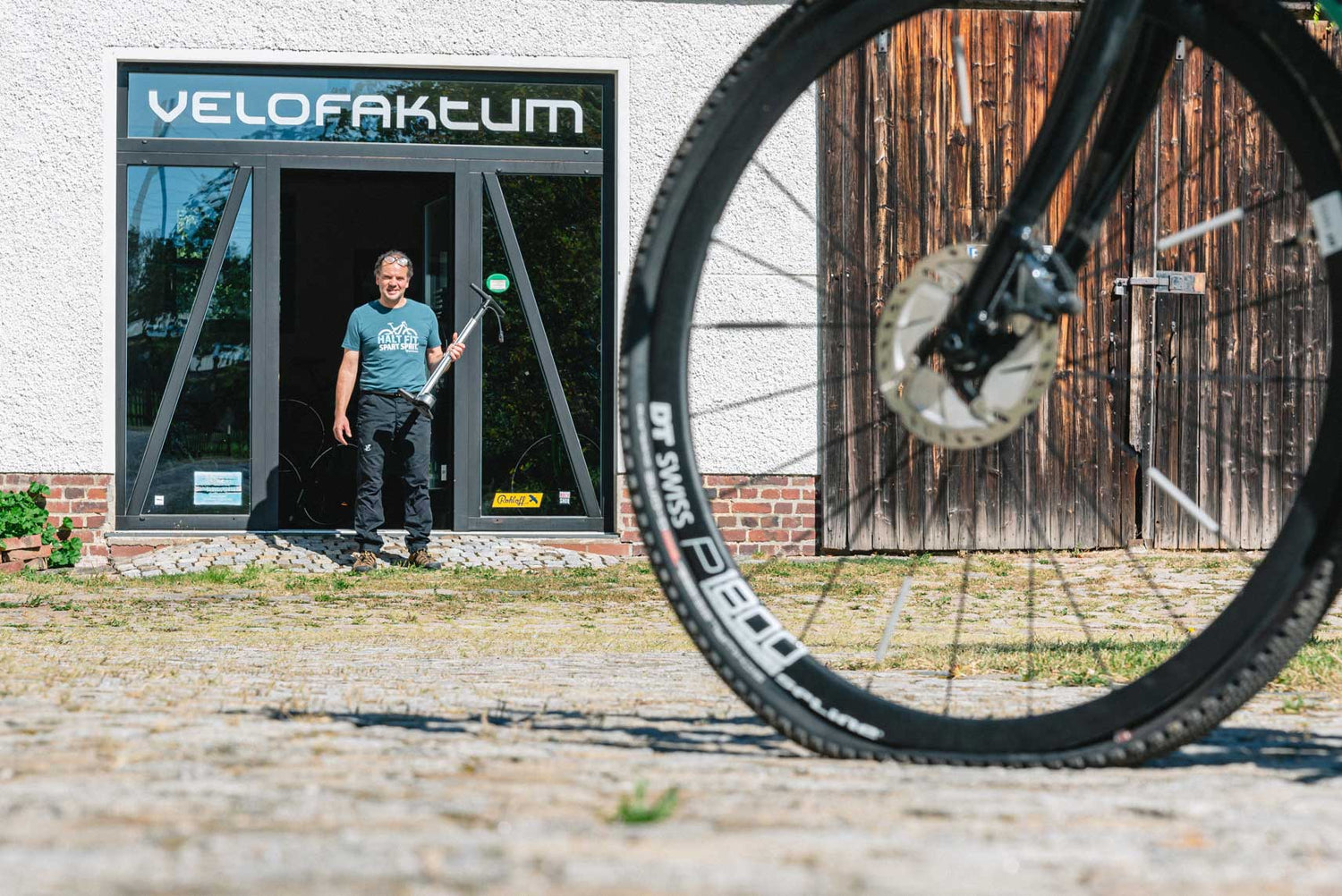 Inhaber Andreas vor seinem Geschäft Velofaktum bei der Inspektion eines Fahrrades.