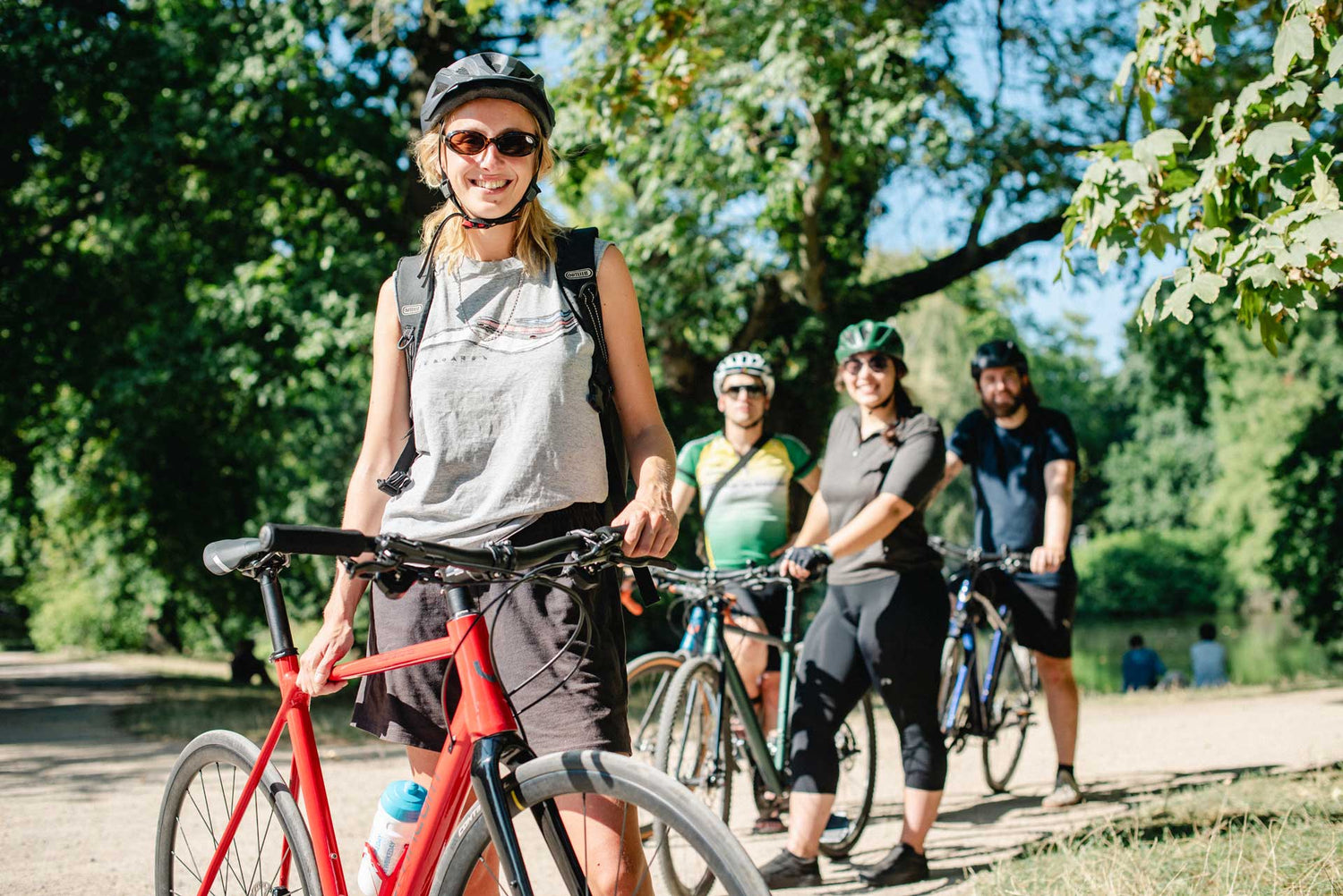 Junge Radfahrerin mit Freunden im Park bei schönem Wetter.